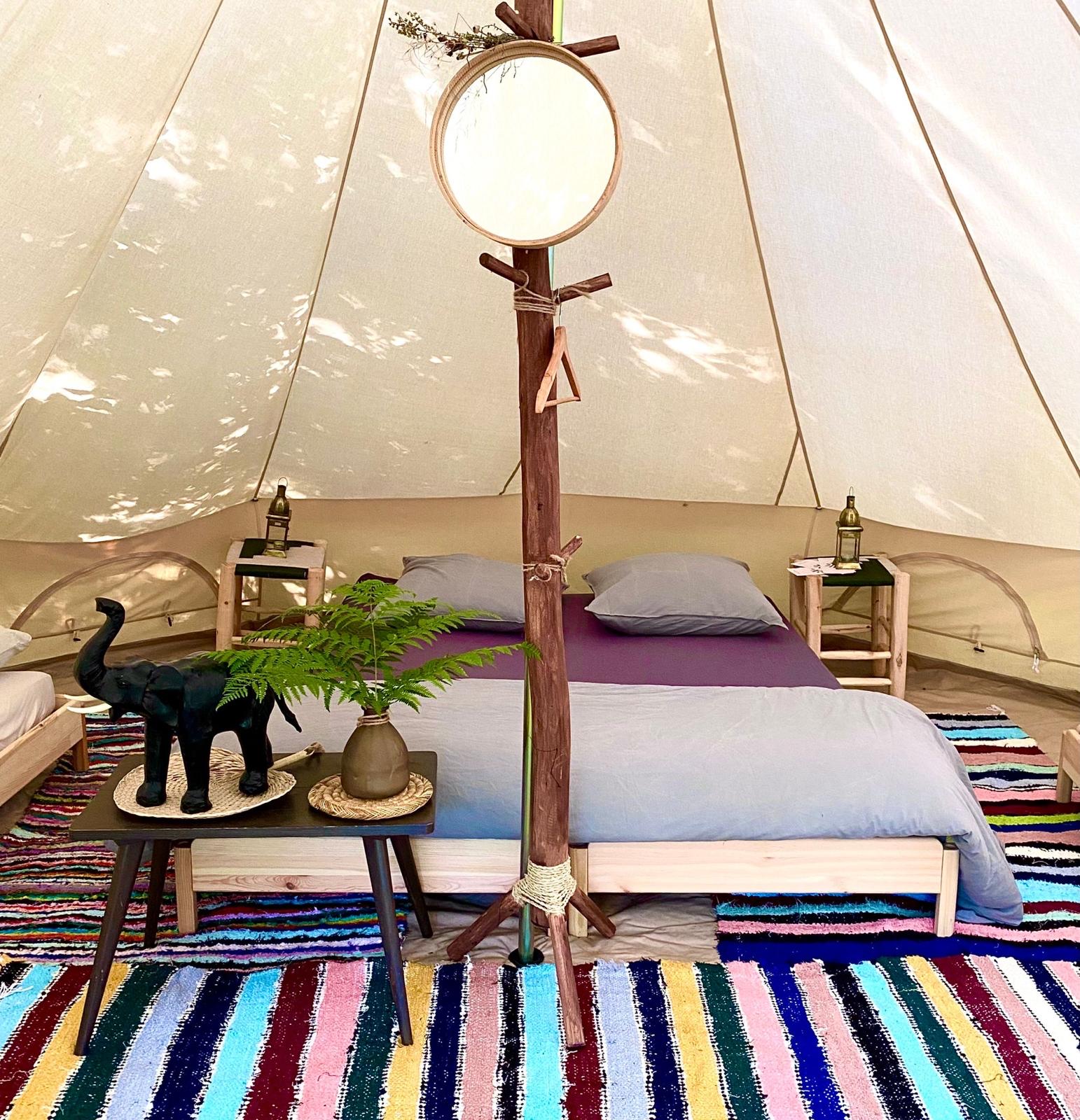 Une chambre Kârma Hôtel sous toile, avec un lit double et des tapis colorés