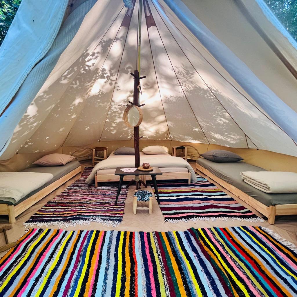Une chambre Kârma Hôtel sous toile, avec plusieurs lits et des tapis colorés